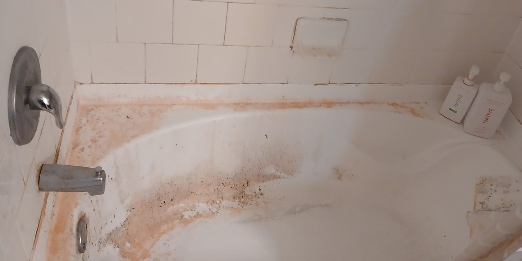 Stained bathtub and tile before a deep cleaning in San Jose